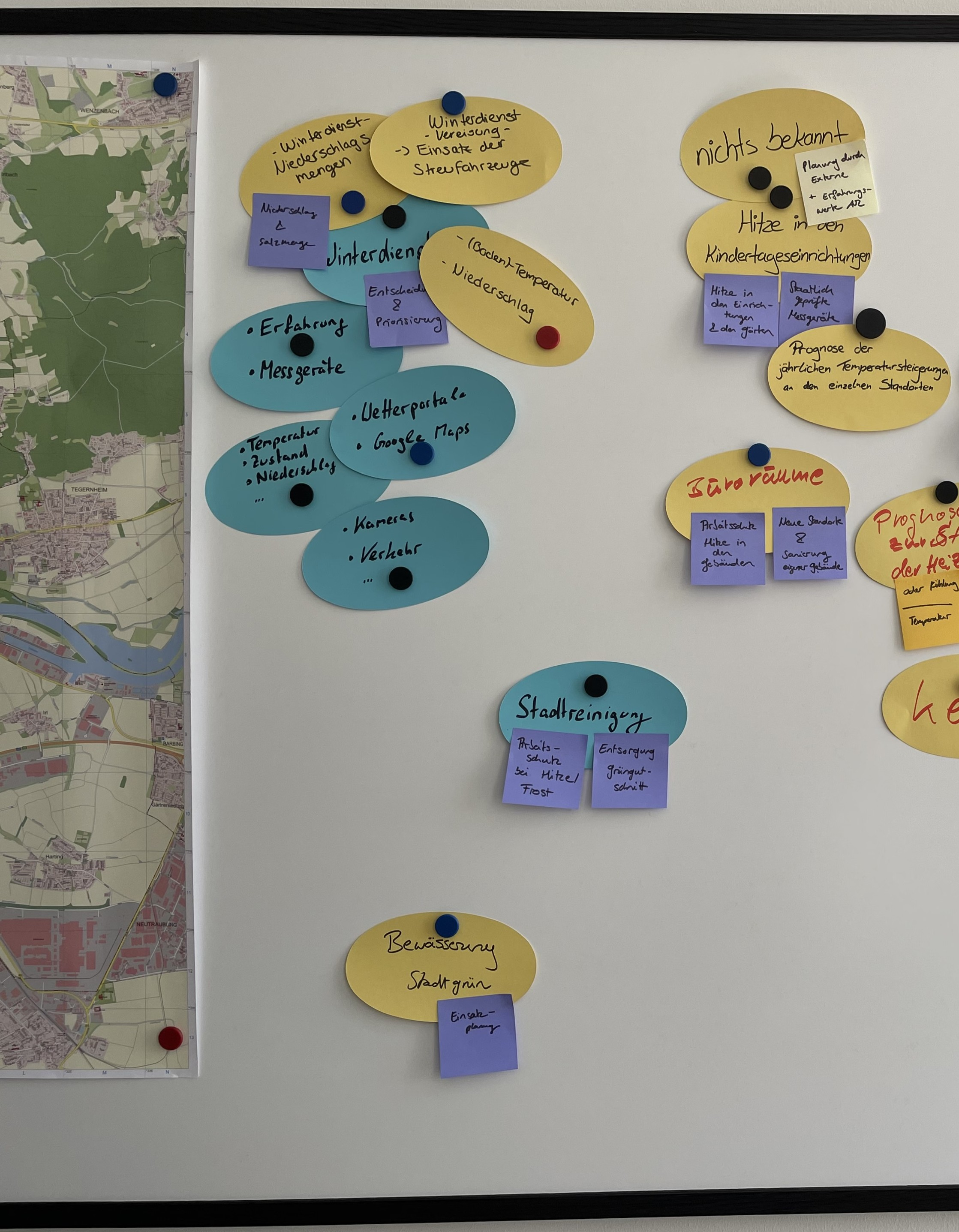 Several pieces of paper are attached to a magnetic board next to a map. They illustrate the brainstorming process when designing sensor networks.